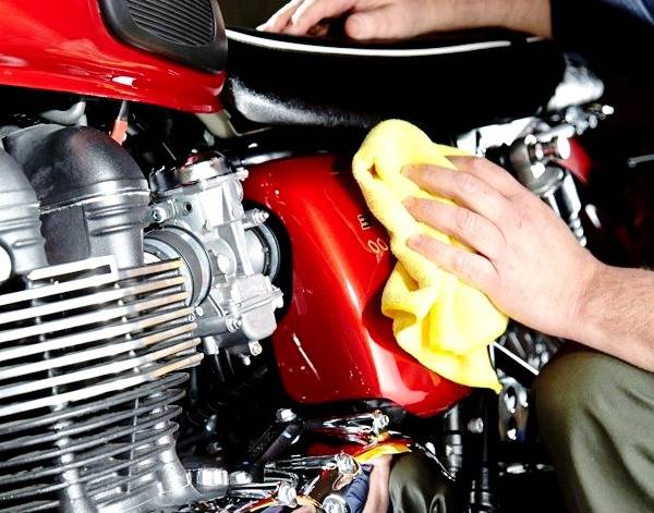 نمایه ای از یه دست که با یه حوله زرد رنگ در حال تمییز و خشک کردن بدنه موتورسیکلت است